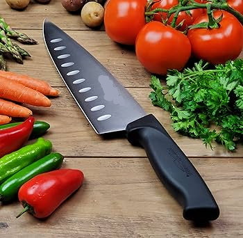 Chef's knife on a wooden surface with vegetables