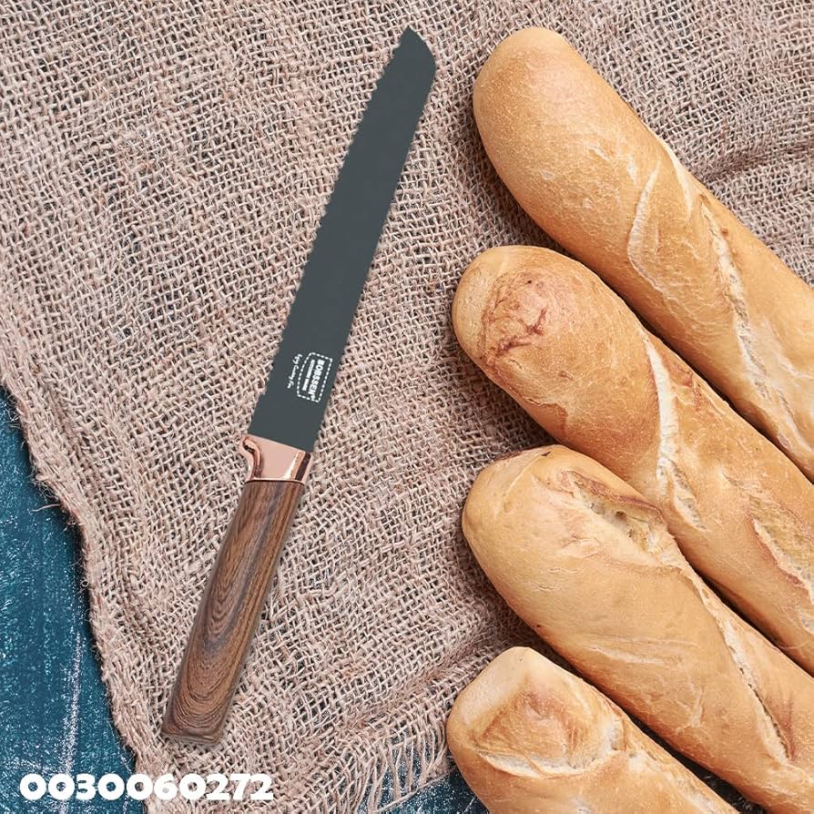 Bread knife with wooden handle next to two baguettes on a textured fabric background