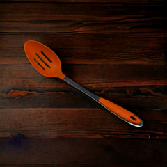Orange slotted spoon on a wooden surface