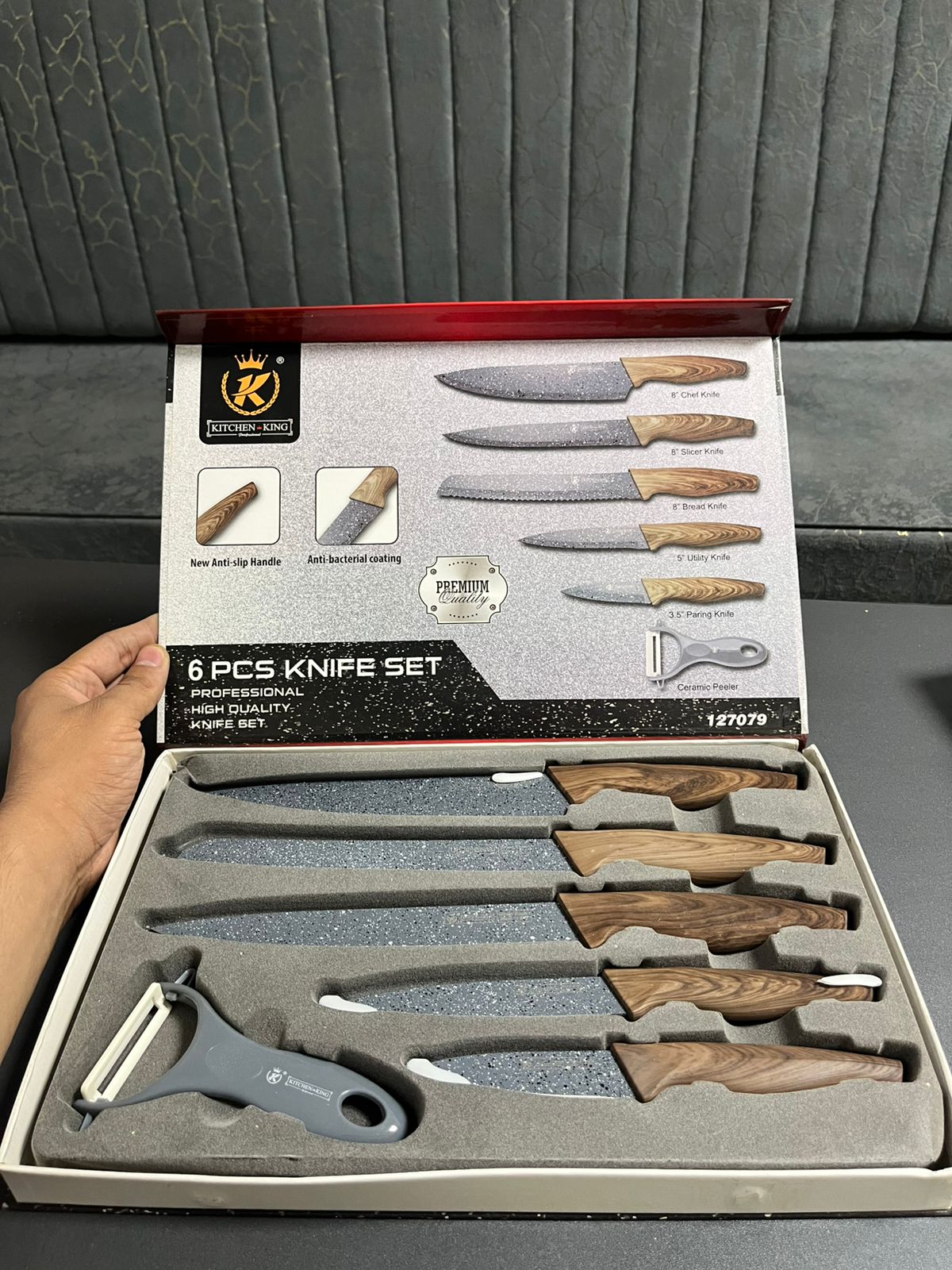 6-piece knife set in a box held by a hand against a gray background