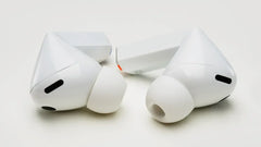 White wireless earbuds with charging case on a light gray background